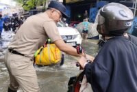 TERPANTAU: Lurah Kembangan Selatan, RM Pradana Putra saat tinjau banjir dan imbau para pengendara. (Foto: Istimewa).