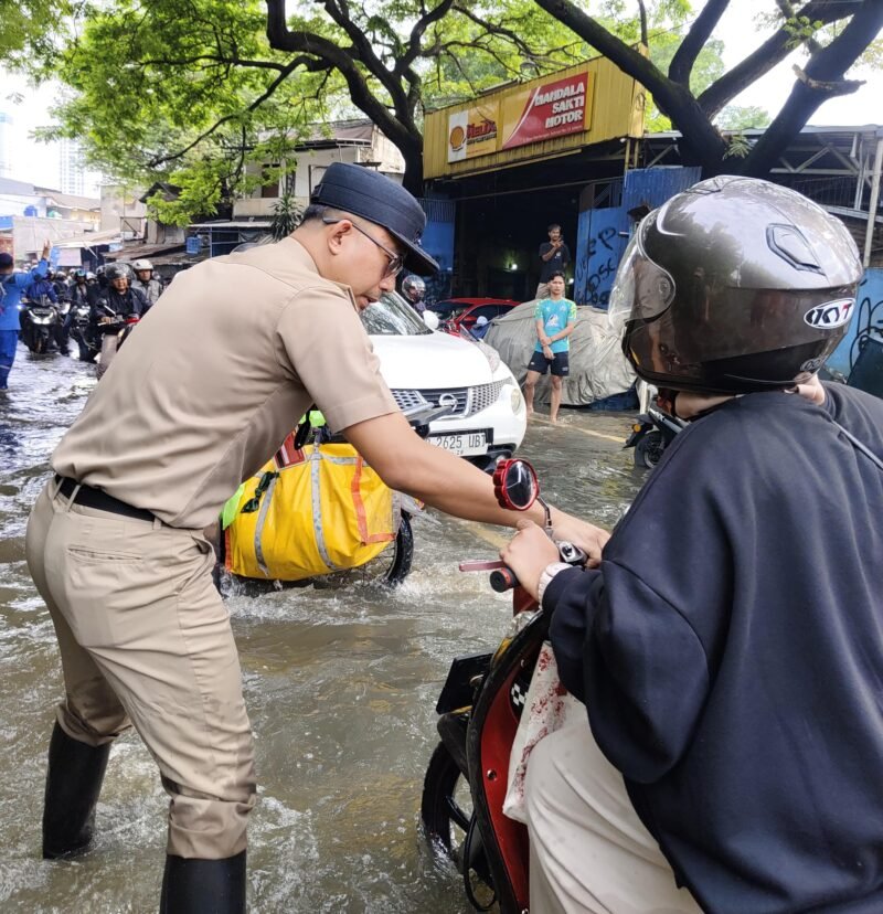TERPANTAU: Lurah Kembangan Selatan, RM Pradana Putra saat tinjau banjir dan imbau para pengendara. (Foto: Istimewa).