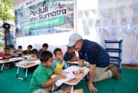 POTRET - Wakil Bupati Aceh Tamiang, Ismail menyaksikan penyerahan sepatu bagi anak penghuni Huntara Aceh Tamiang oleh Direktur Utama PTPN IV PalmCo. Selain menyiapkan lahan untuk pembangunan hunian, dukungan psikososial terus diperkuat PTPN IV melalui pemberian sepatu sekolah dan peluncuran Sekolah Darurat bekerjasama dengan benihbaik.com yang didirikan oleh Andy F Noya. (Foto: Istimewa).